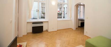A spacious room with large windows, a wooden floor, and a green bench.