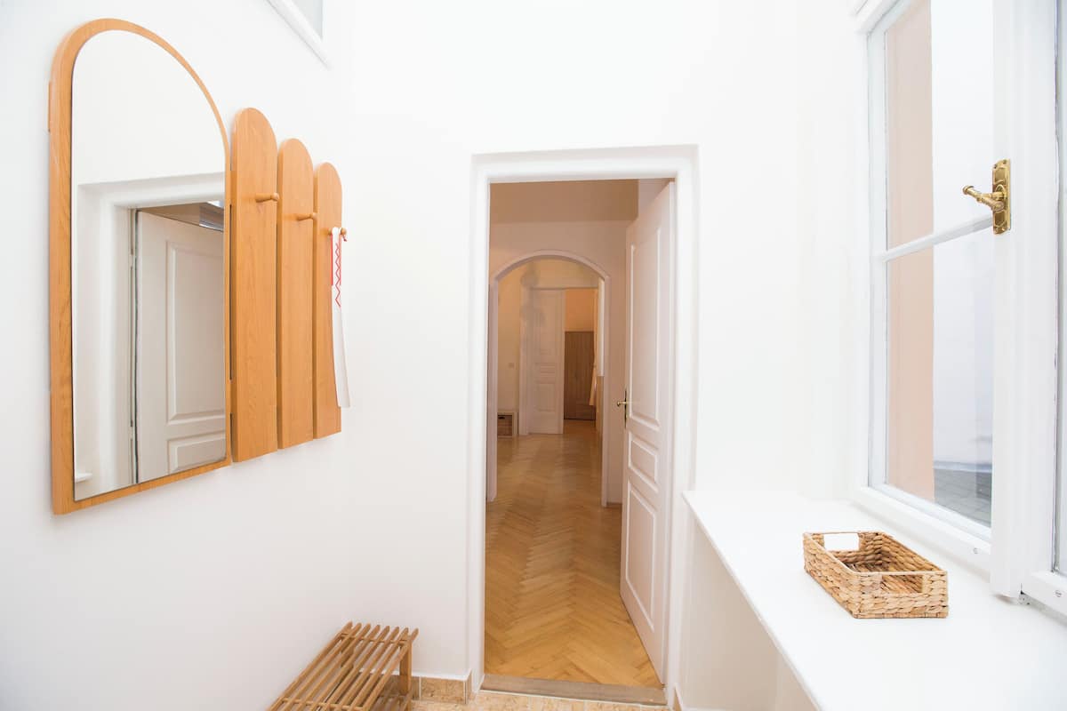 Ein Flur mit einer Holztür, einem Spiegel, einem Fenster mit Korb und einem Fischgr ätparkett.