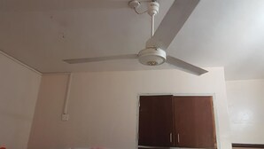 Een kamer met een plafondventilator, een kledingkast en een bed met dekbed.
