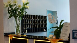 Ein Empfangsschalter mit Schwarz-Weiß-Design, zwei große beleuchtete Tafeln und eine Anordnung weißer Orchideen.