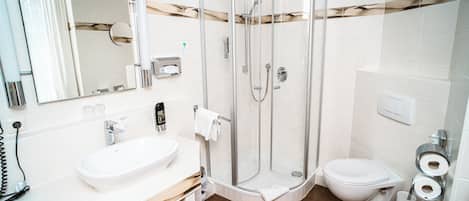 Ein modernes Badezimmer mit einer Duschkabine, einem weißen Waschbecken und einer Toilette.