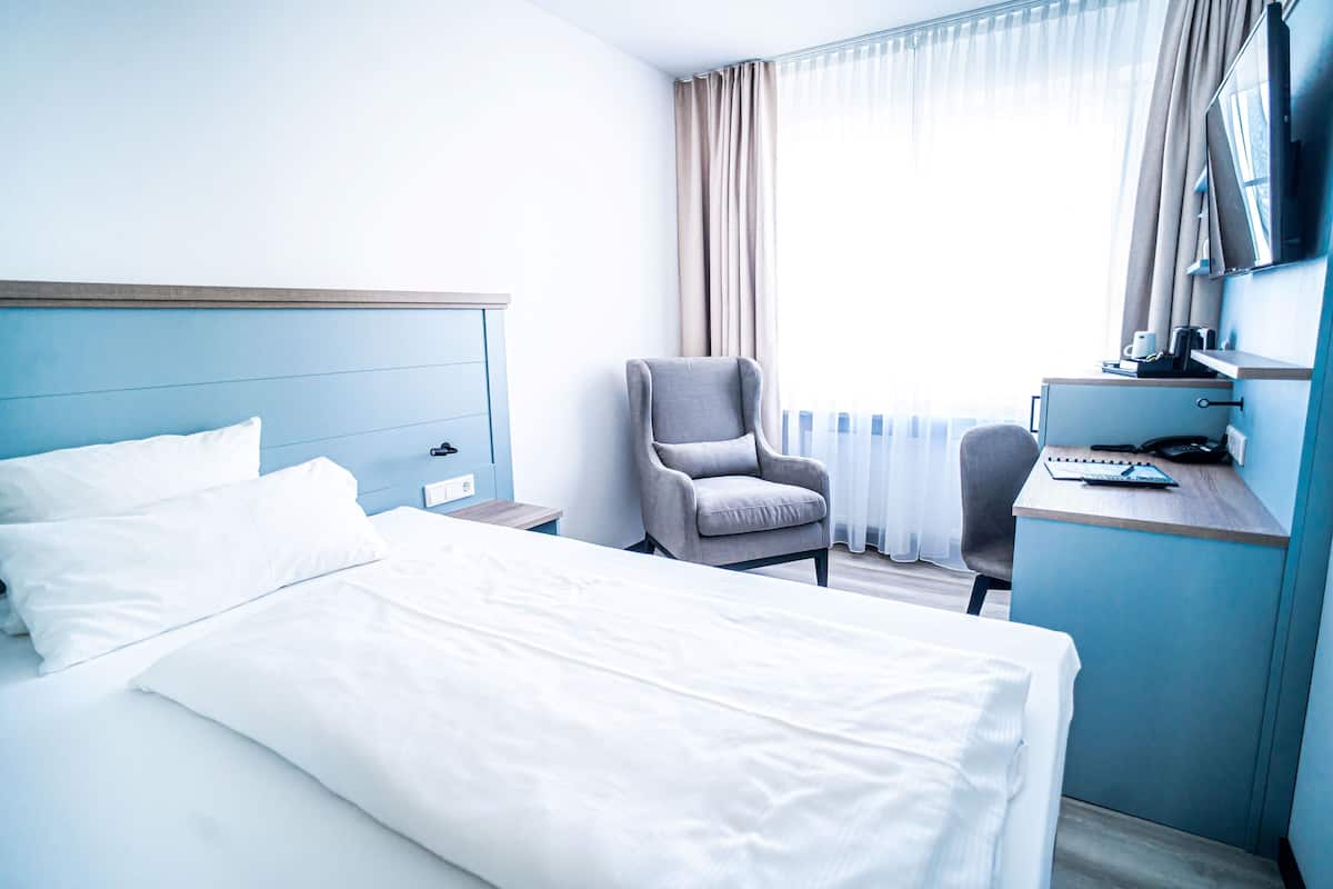 Ein Hotelzimmer mit Bett, Schreibtisch, Stuhl und Fernseher.