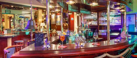 Zona de bar con mostrador de madera, taburetes y diversos objetos de bar.
