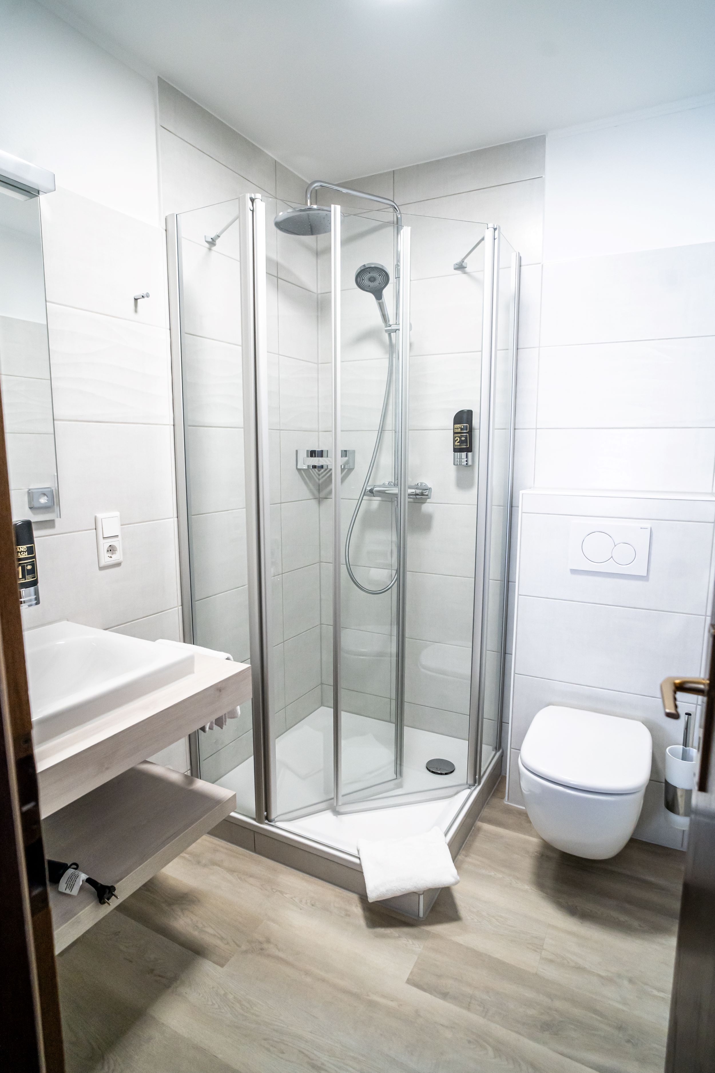 Een moderne badkamer met een douchecabine van glas, een witte wastafel en een toilet.