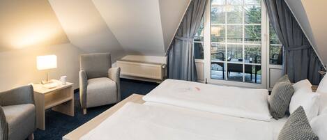 A hotel room with two beds, a desk, a chair, and a window with curtains.