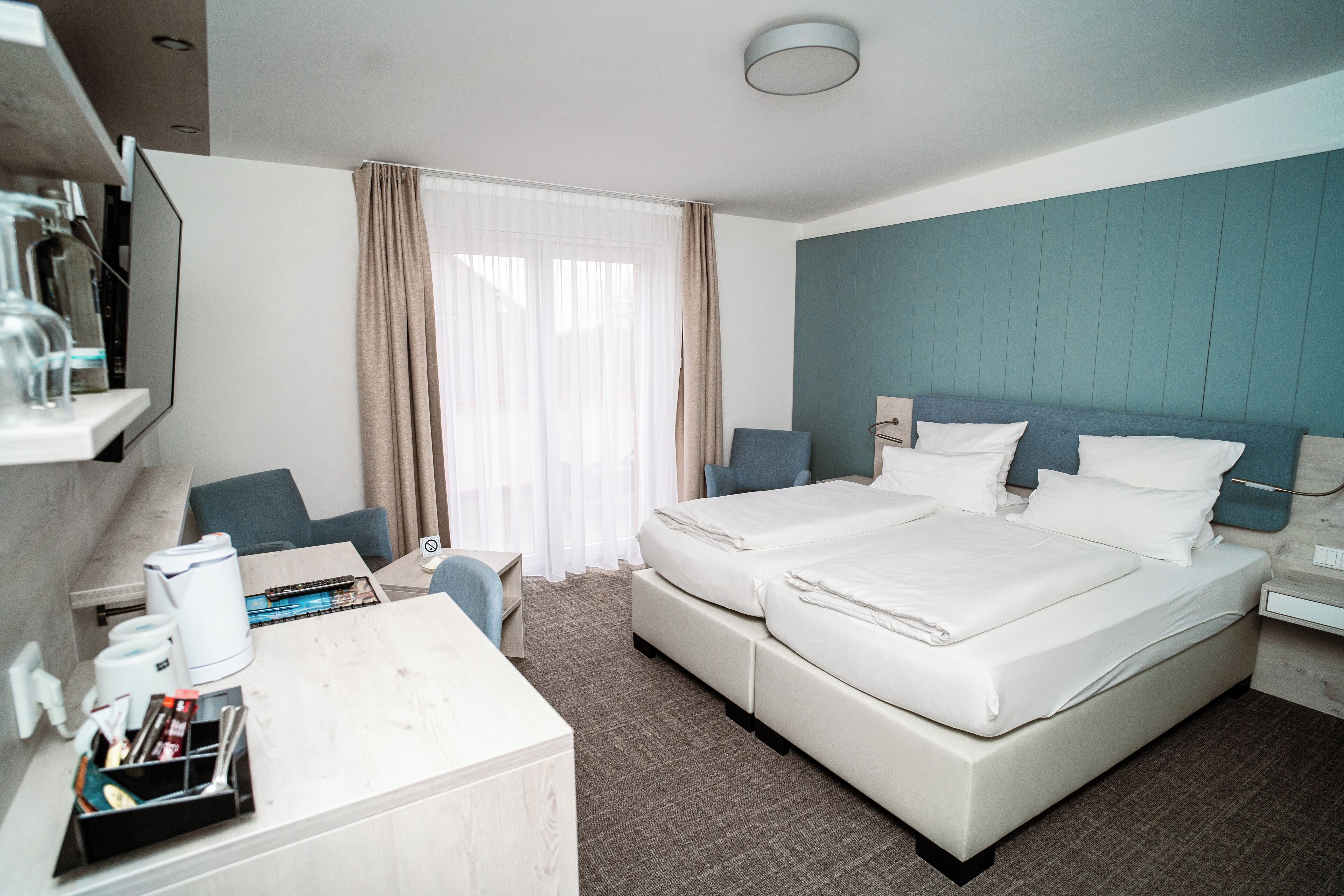 Hotellihuone, jossa on sänky, yöpöydät, työpöytä ja tuoli.