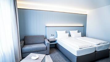 Una habitación de hotel con una cama, un sofá, una mesita de noche y una pequeña mesa.