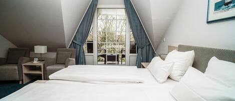 Una habitación de hotel con una cama grande, un sofá, un escritorio y una ventana con cortinas.