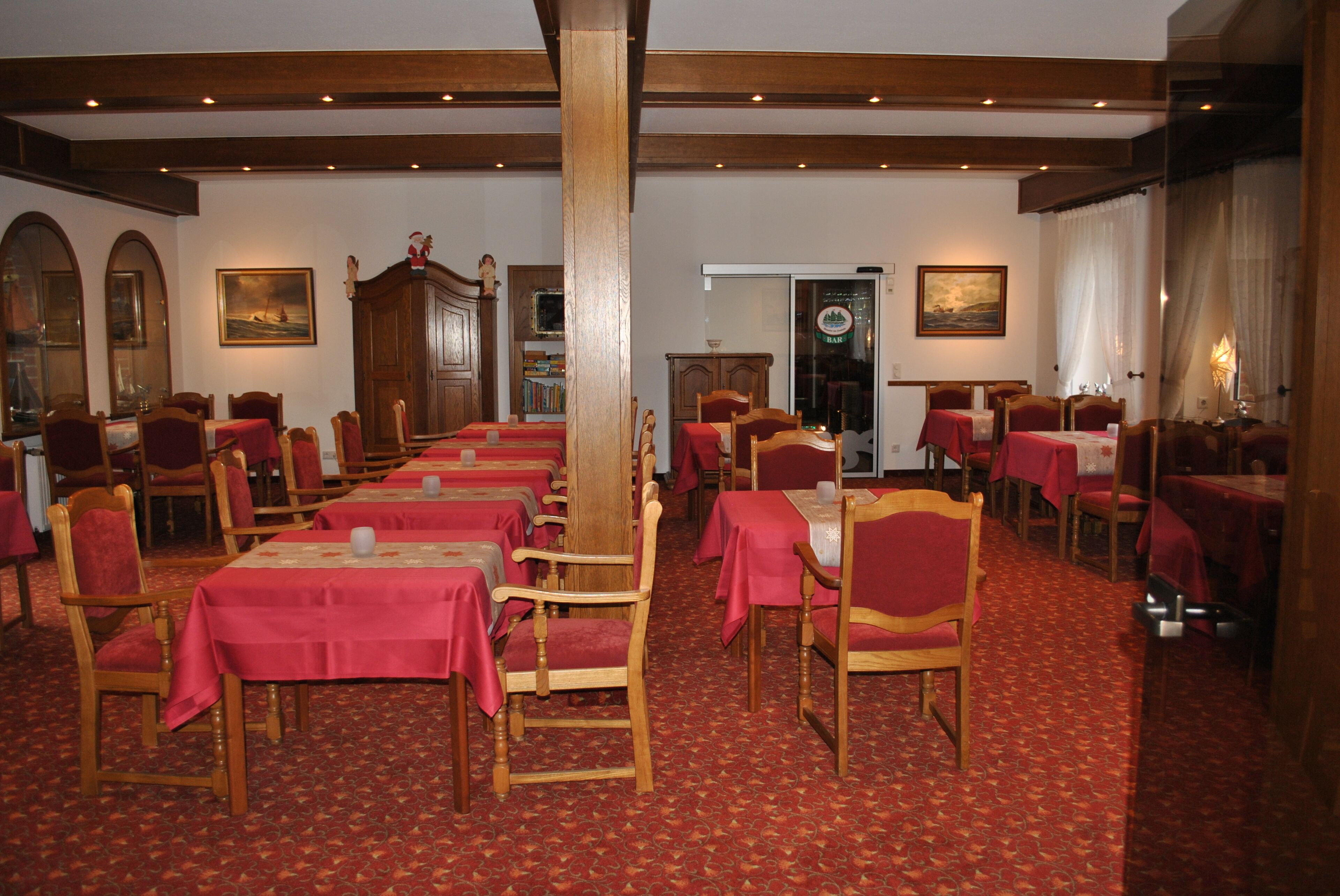 A dining area with multiple tables and chairs, wooden furniture, and a patterned carpet.