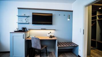 Ein gemütliches Schlafzimmer mit Schreibtisch, Stuhl und einem an der Wand befestigten Fernseher.