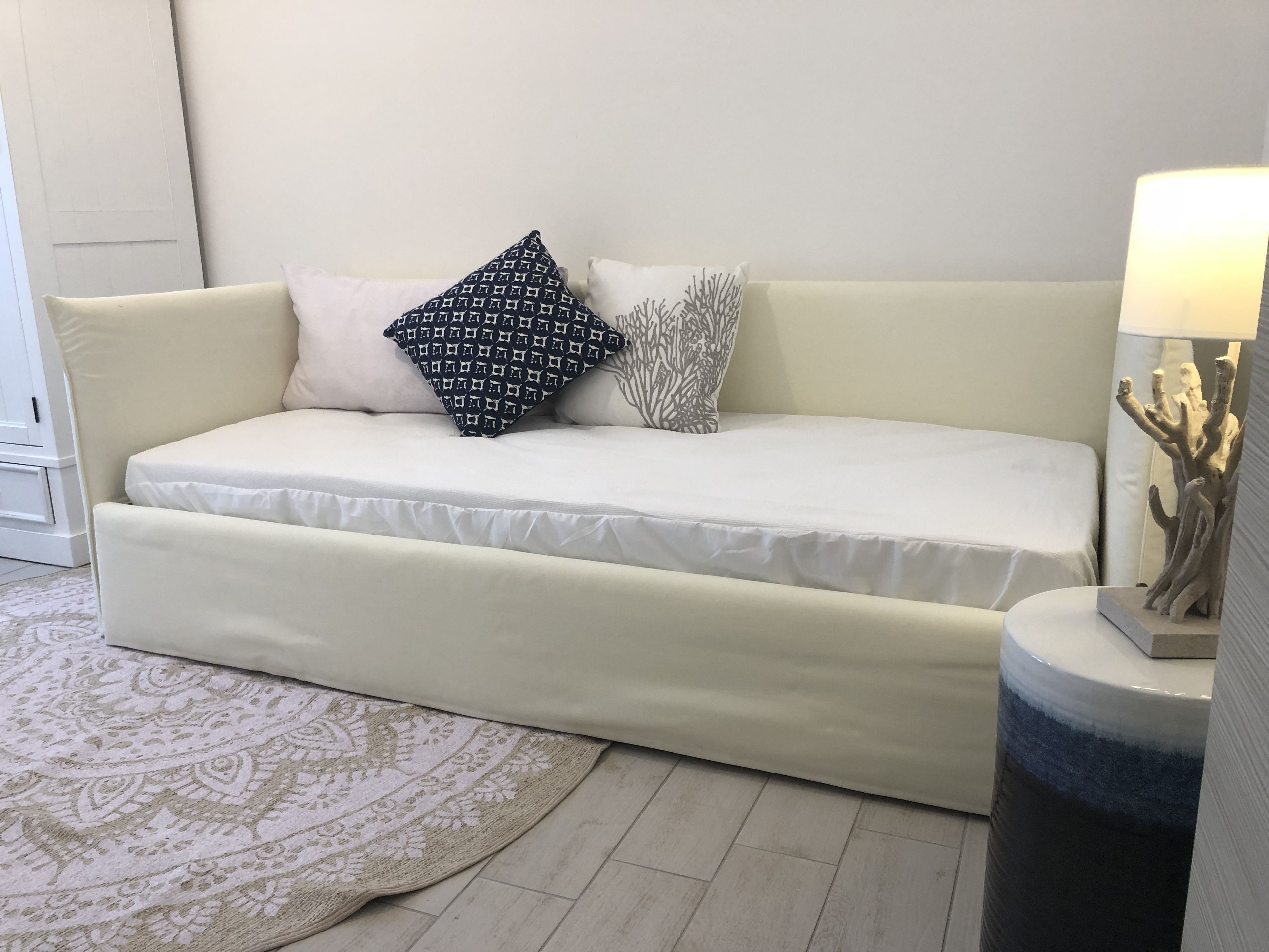 Una sala de estar moderna con un sofá color crema, cojines estampados, una rama decorativa y una alfombra con diseño.