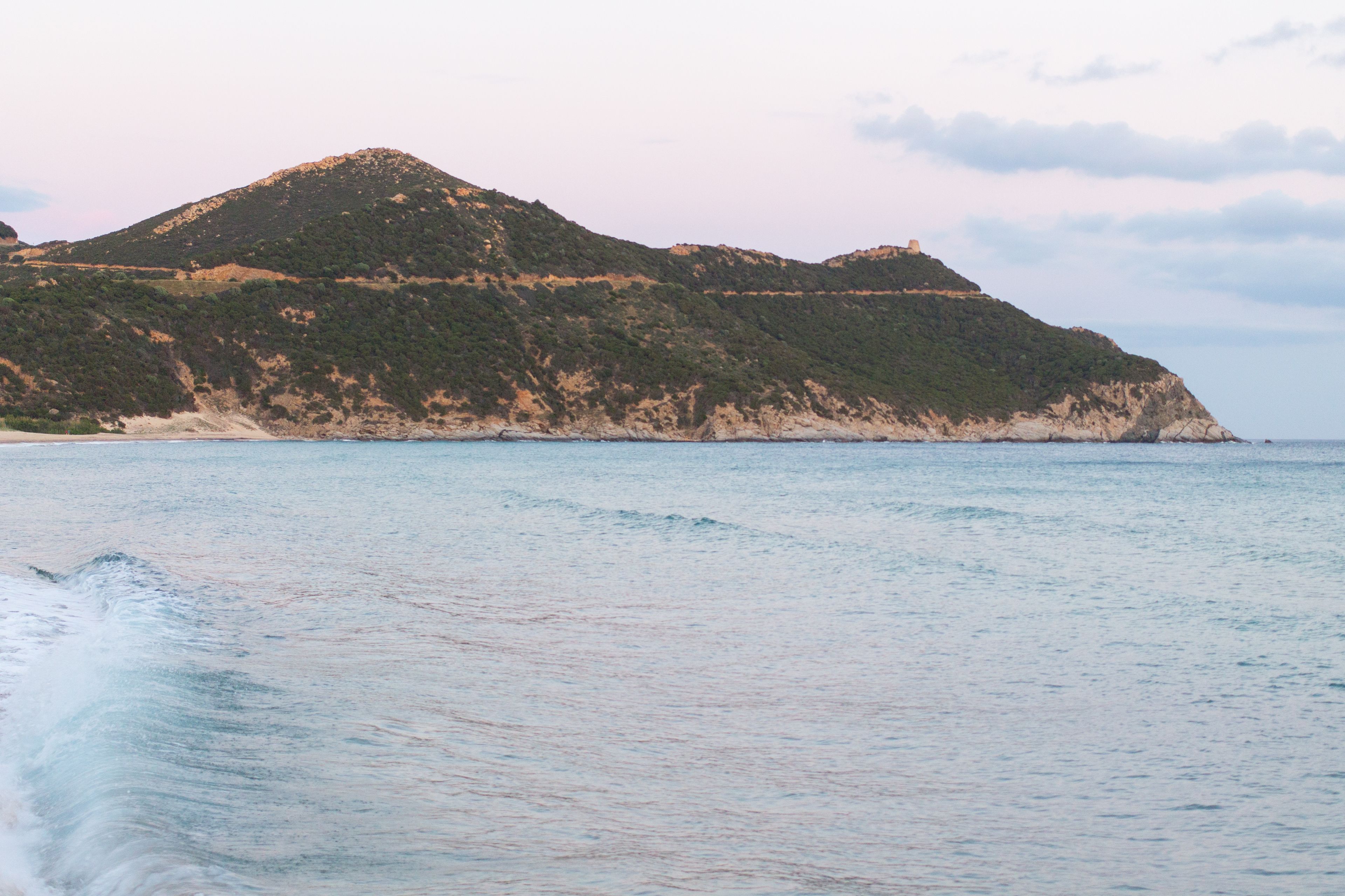 Un paysage côtier avec une colline et une plage.