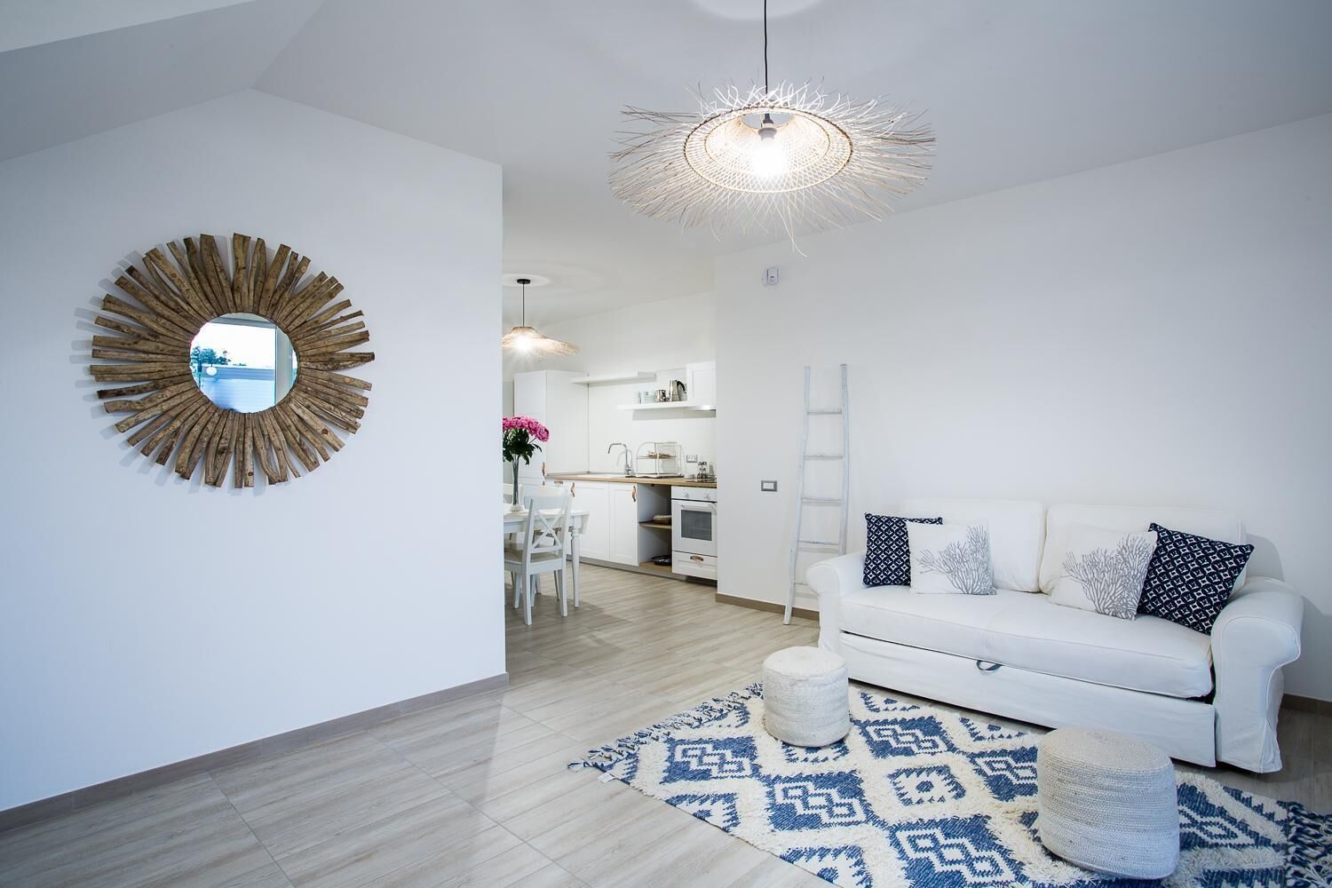 A modern living room with a white sofa, a patterned rug, and a wooden-framed mirror.
