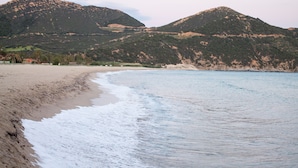 Une plage aux vagues douces, un rivage sablonneux et des collines en arrière-plan.