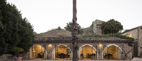 A courtyard with stone arches, a palm tree, and a building with a tiled roof.