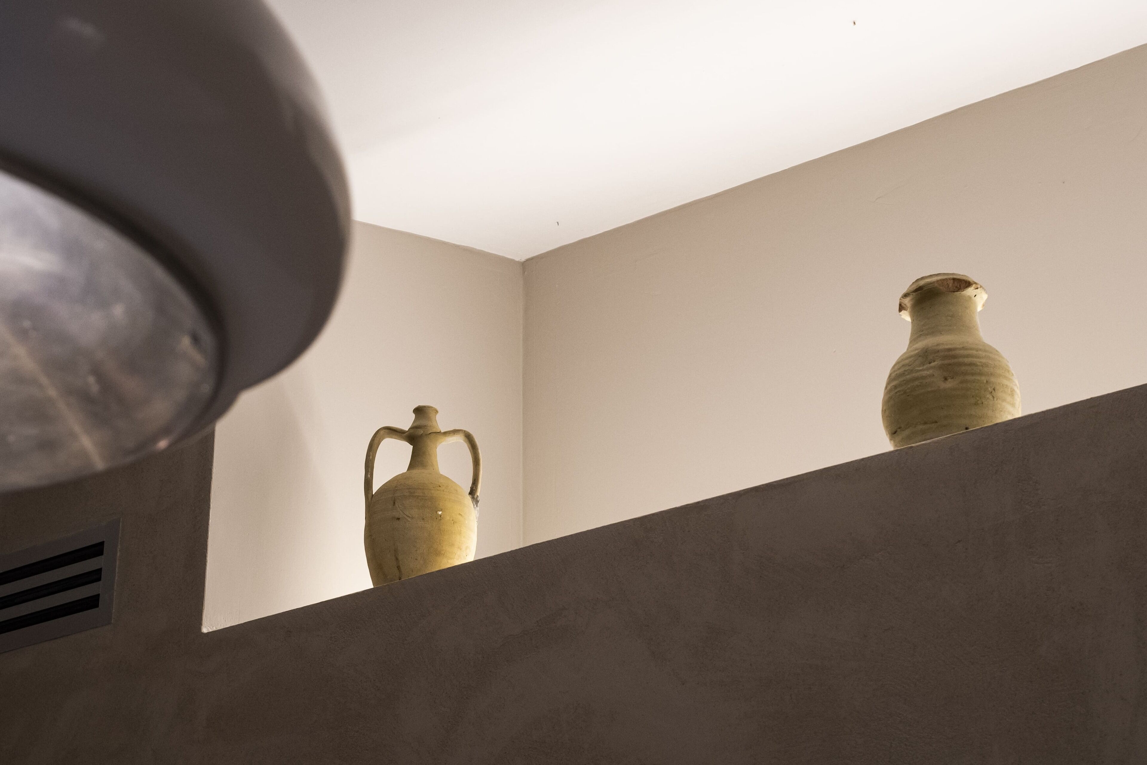 Two ceramic vases on a shelf against a plain wall.