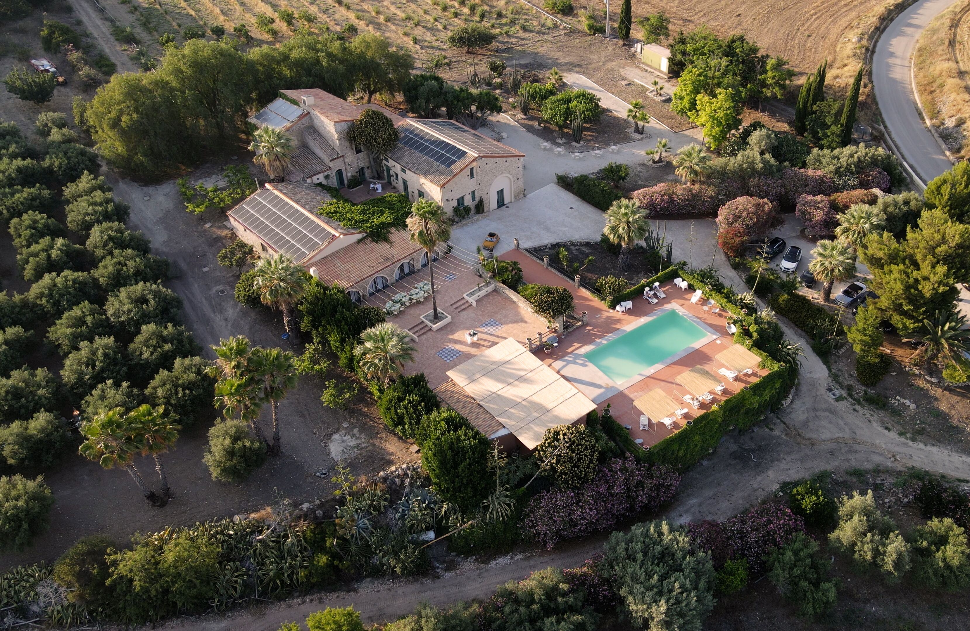 An aerial view of a property with a swimming pool, solar panels, and a landscaped garden.