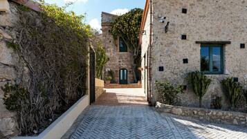 A narrow stone pathway leading to a building with a green door and a window.