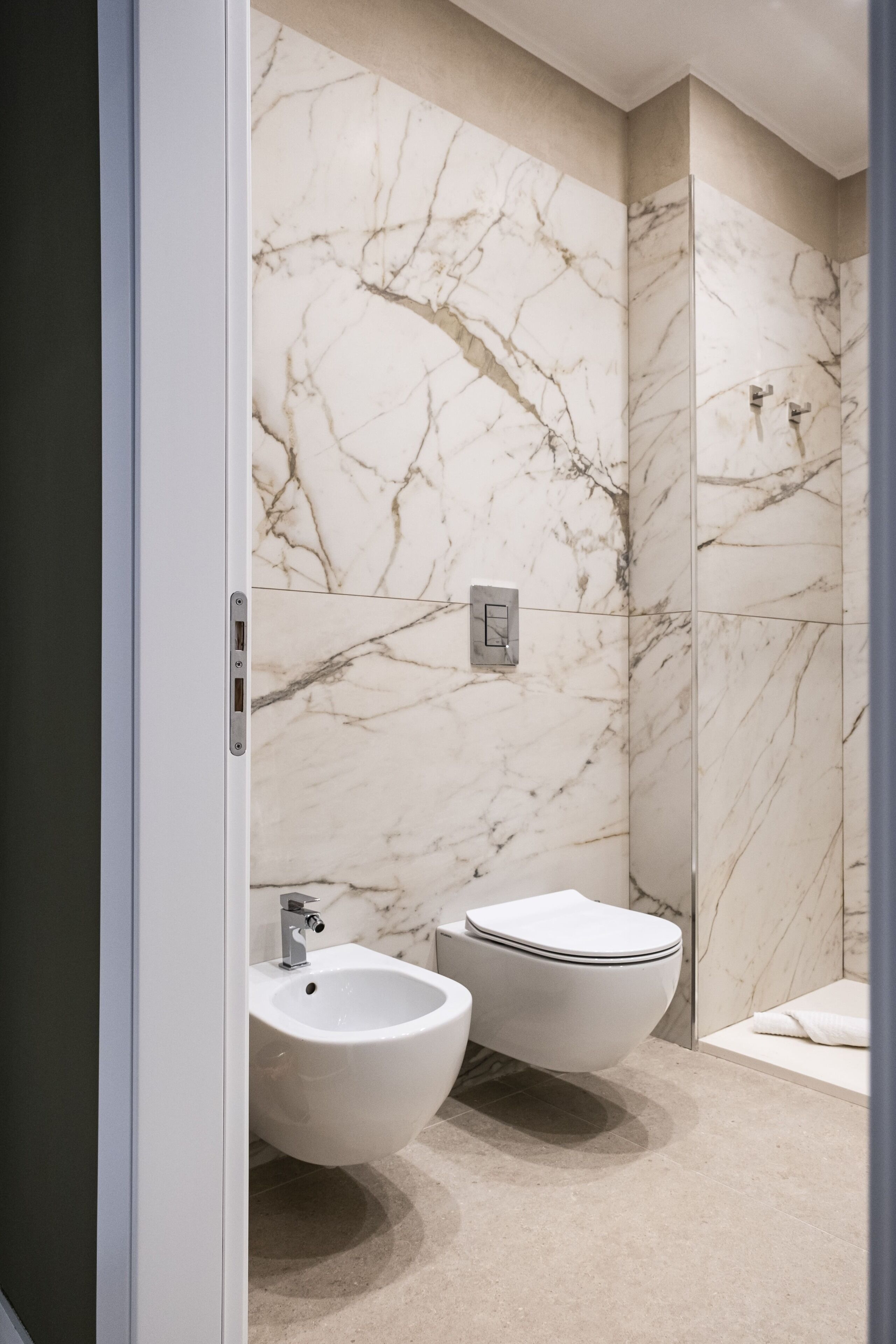 Une salle de bain moderne avec des murs en marbre, un bidet et des toilettes.