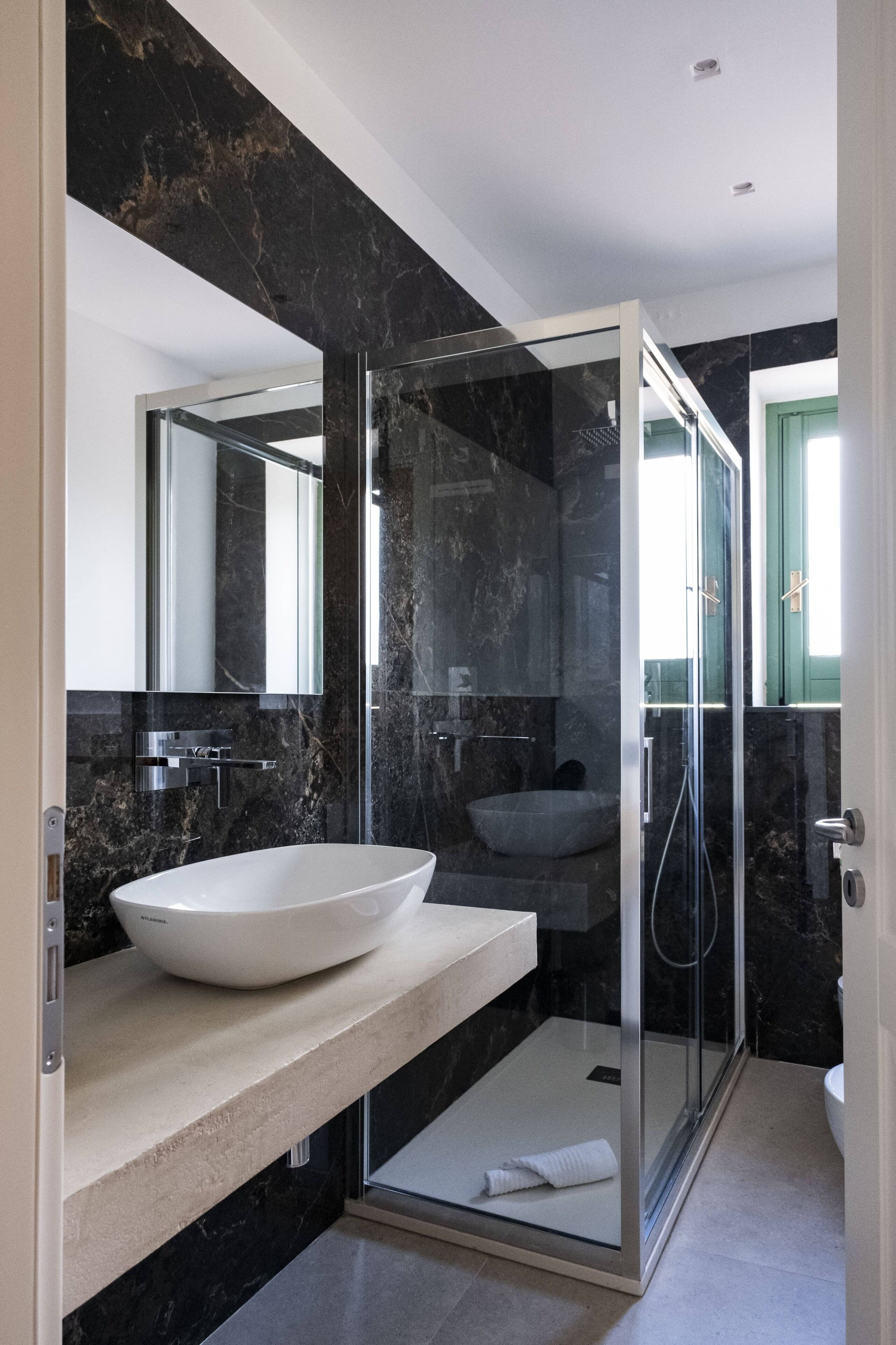 Un bagno moderno con una vasca freestanding, una doccia con box in vetro e un rivestimento in marmo.