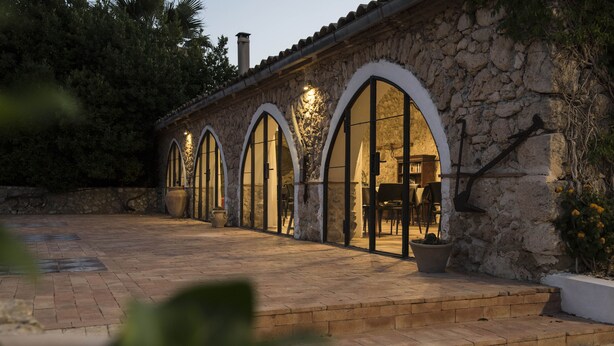 Un edificio de piedra con ventanas de arco y un patio empedrado.