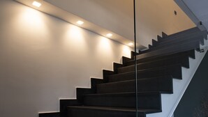 Una escalera moderna con barandilla de vidrio e iluminación empotrada.
