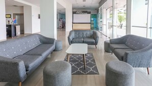 Un hall d’entrée moderne avec des canapés gris, des poufs et une table basse blanche.