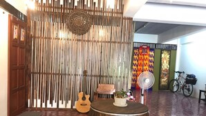 Una habitación con pared de listones de madera, una guitarra, un ventilador y una bicicleta.