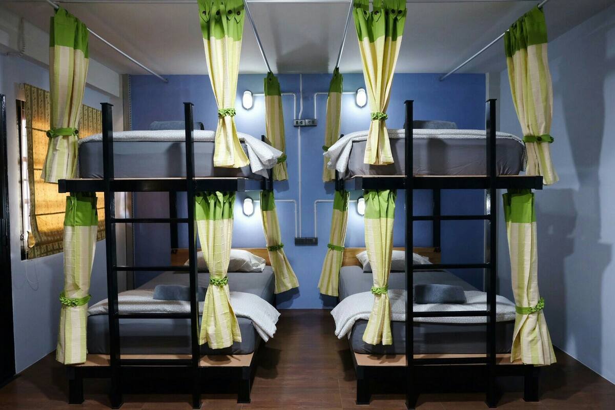 A room with bunk beds, each with a curtain. There are wall-mounted lights and a mirror above the beds.