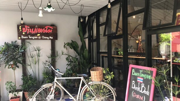Una bicicleta estacionada frente a un edificio con un letrero que dice "Baan Tangmo @ Chiang Mai".