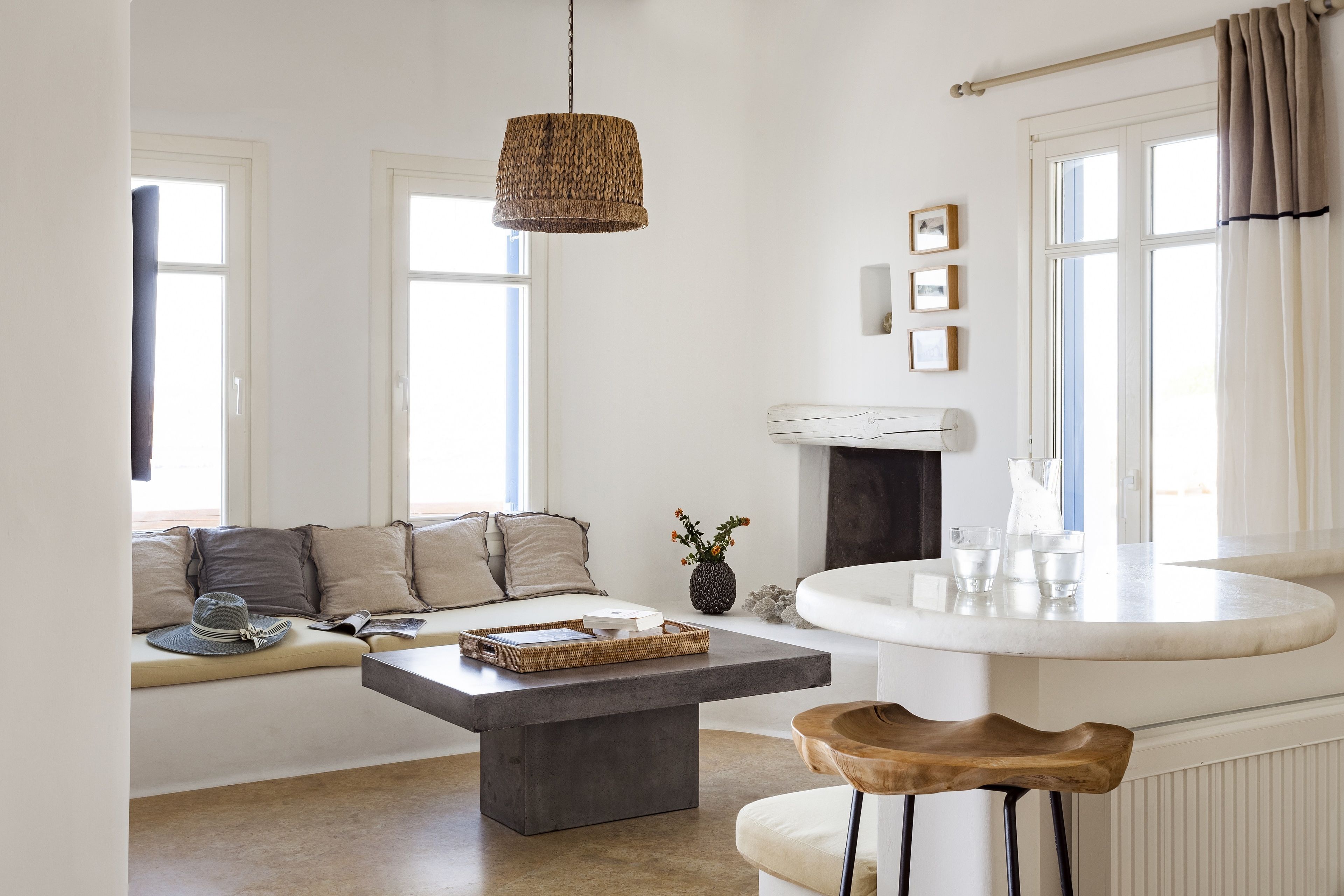 A modern living room with a sofa, a coffee table, a hanging light fixture, and a fireplace.