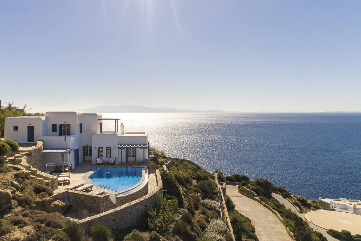 A white villa with a pool overlooking the sea.