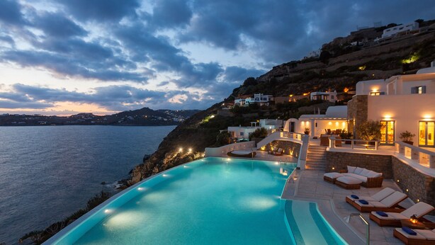 A poolside area with lounge chairs and a view of the sea. - AGL Luxury Villas (Mykonos)