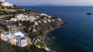 A coastal resort with multiple white buildings, a swimming pool, and a rocky shoreline. - AGL Luxury Villas (Mykonos)