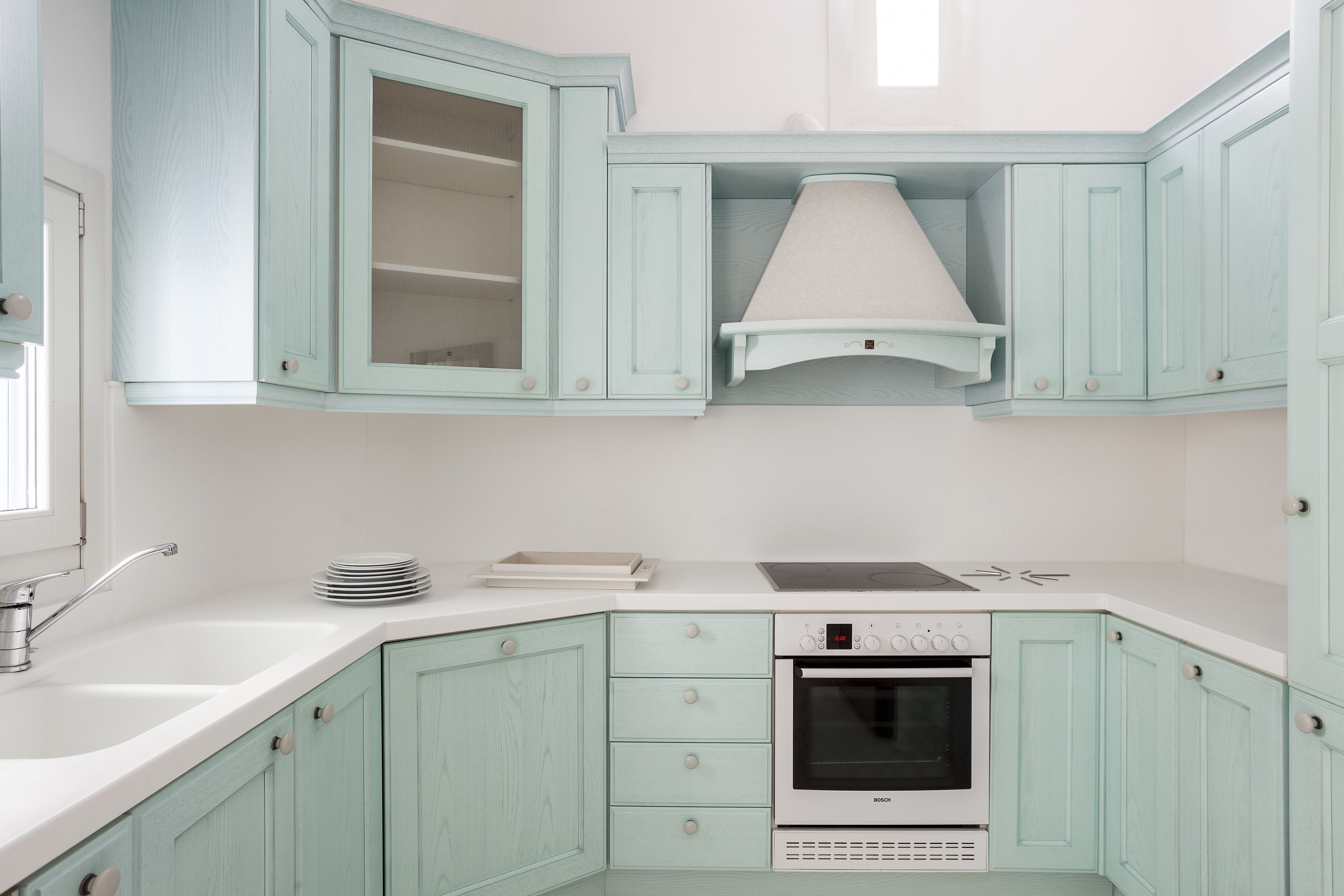 Una cocina con armarios azul claro, un horno Bosch y una encimera blanca.