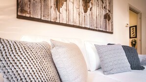 A neatly made bed with patterned pillows and a rustic wall art piece above it. - La Contrada del Pittore (Como)