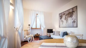 A cozy room with a wooden table, a white sofa, a TV, and a world map artwork on the wall. - La Contrada del Pittore (Como)