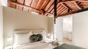 A bedroom with a wooden ceiling, a bed with white bedding, two bedside lamps, and a tray with a cup and a vase. - La Corte delle Rondini (Como)