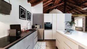 A modern kitchen with a wooden ceiling, white cabinets, and a built-in oven. - La Corte delle Rondini (Como)