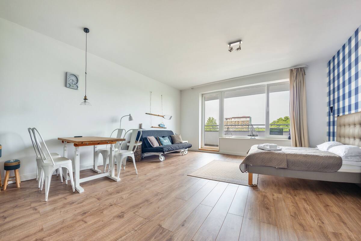 A spacious room with a bed, a sofa, a dining table, and chairs.