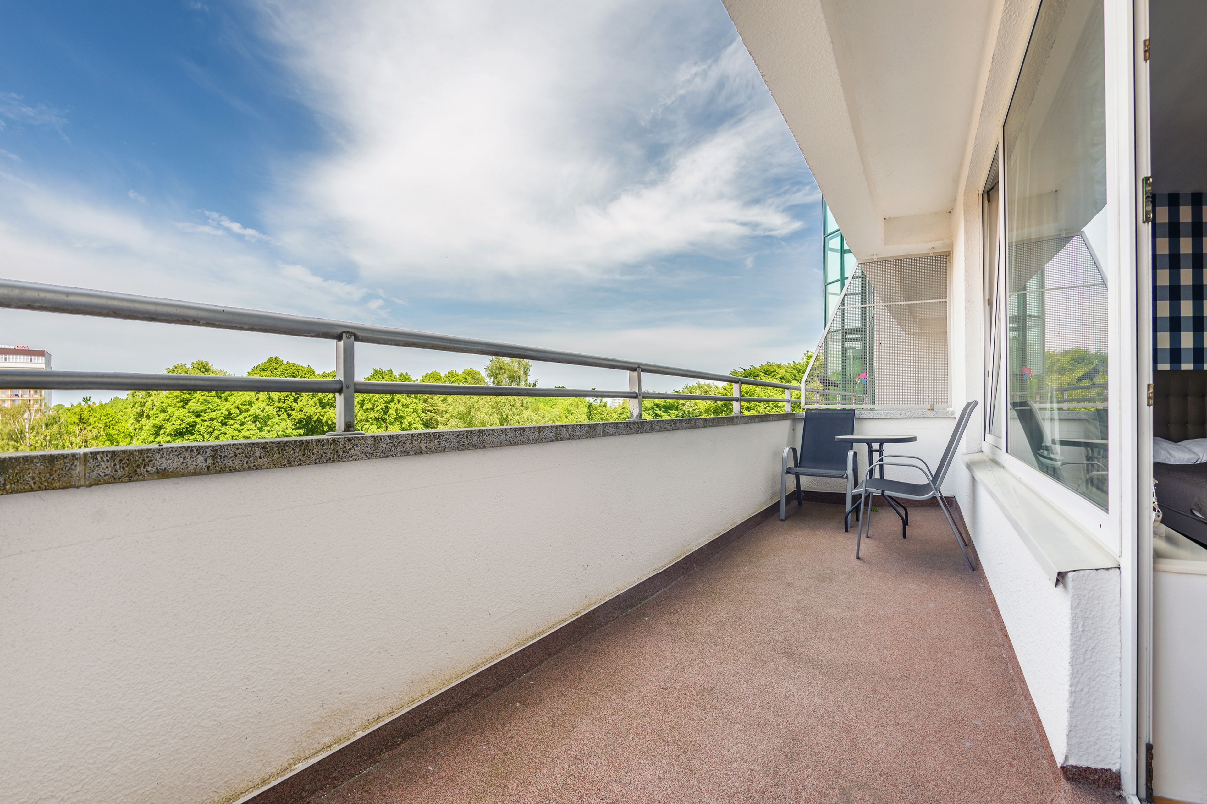 A balcony with a metal railing, a table, and two chairs.