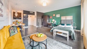 Eine moderne Wohnung mit Küche, Essbereich und Schlafzimmer mit großem Bett und grünen Wänden.