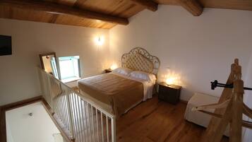 A bedroom with a wooden ceiling, a bed with a headboard, bedside tables, and a crib.