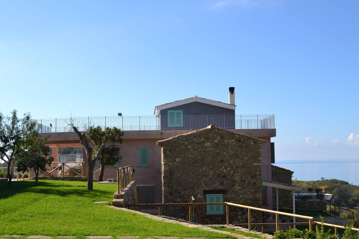 Un bâtiment en pierre doté d’un balcon, d’une pelouse et offrant une vue dégagée sur la mer.