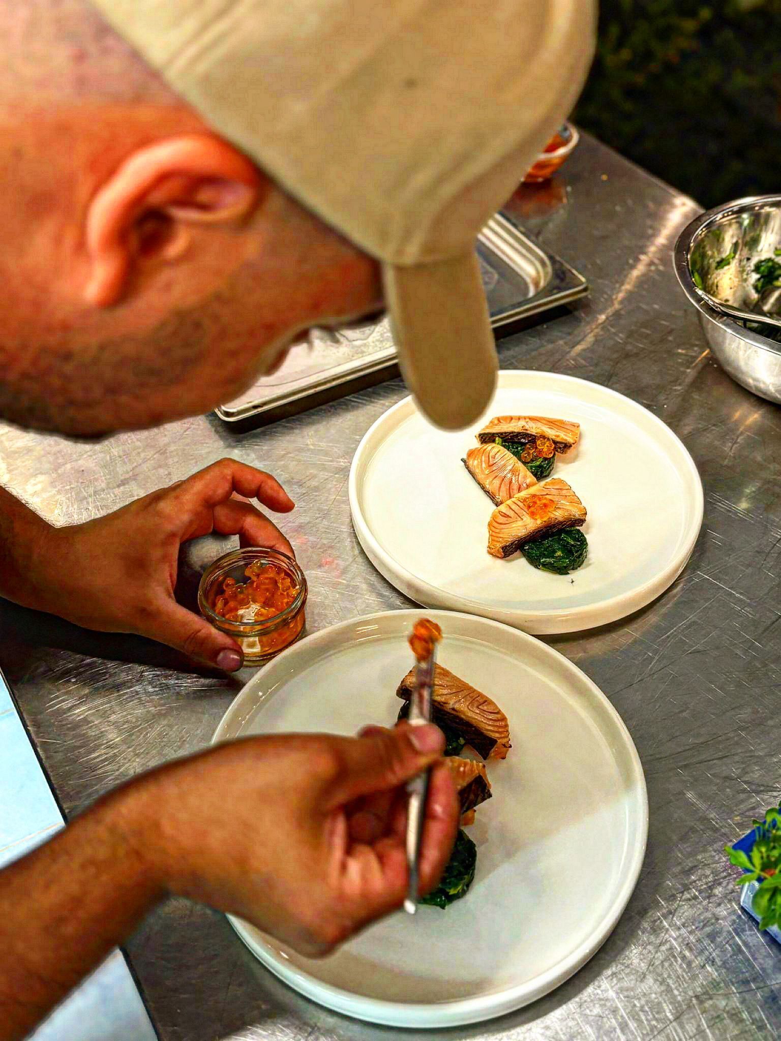 A person serving food on a metal table.