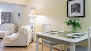 A dining area with a glass table, white chairs, a lamp, and a framed photo on the wall. - Lake Panorama (Como)