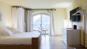 A bedroom with a bed, a dresser, a TV, and a balcony with a table and chairs. - Lake Panorama (Como)