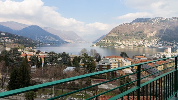 A panoramic view of a lakeside town with buildings and mountains in the background. - Lake Panorama (Como)