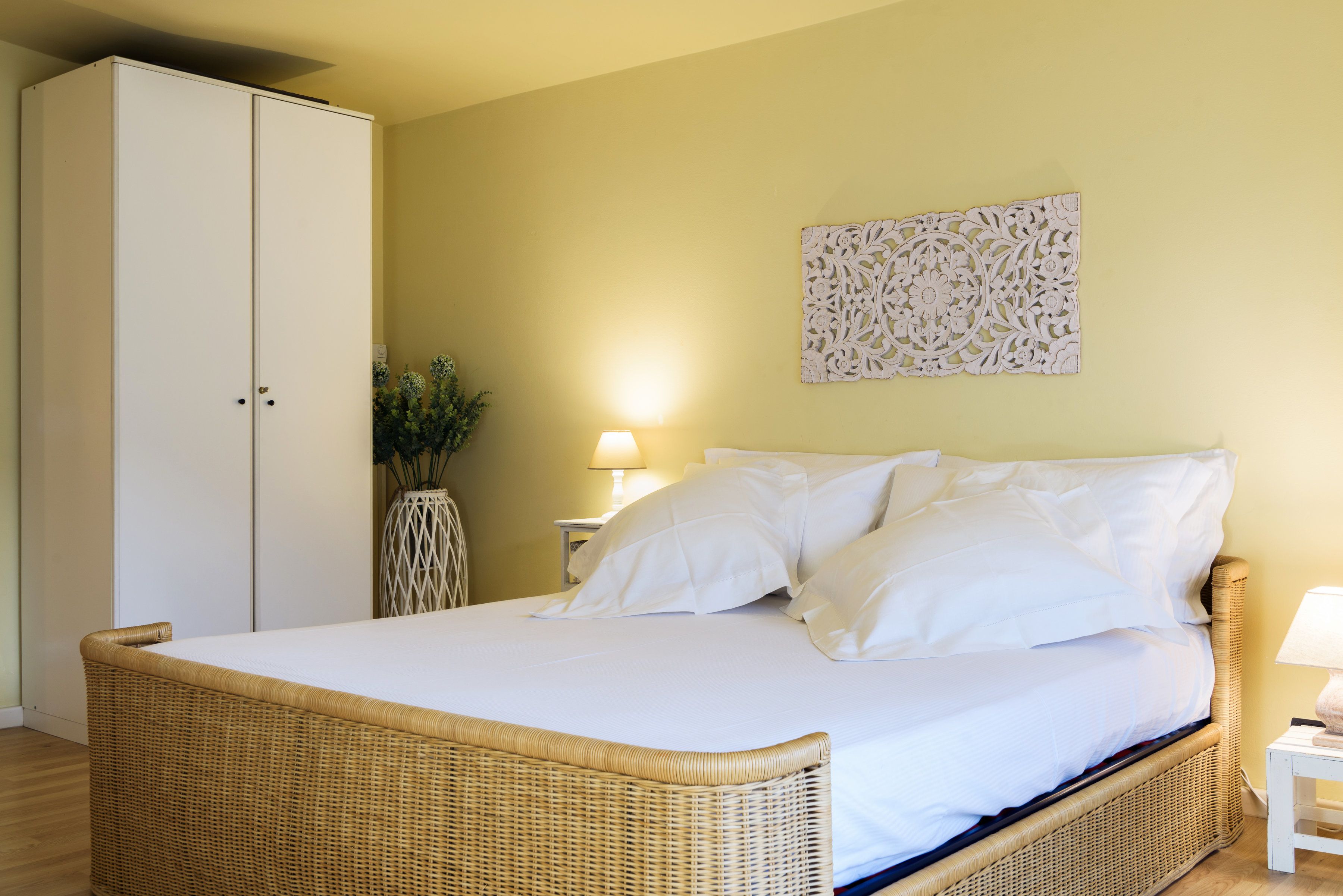 Ein Schlafzimmer mit einem großen Bett, einem Kleiderschrank, einer Wanddekoration und einer Nachttischlampe.