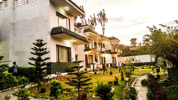 A multi-story residential building with a well-maintained garden and a pathway. - Van Durga Villas & Suites Katra (Reasi)
